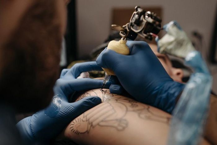 Tattoo artist tattooing a client's arm [Photo: Pavel Danilyuk]