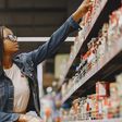 A customer checks labels on products on a supermarket shelf [Image Credit: Gustavo Fring]