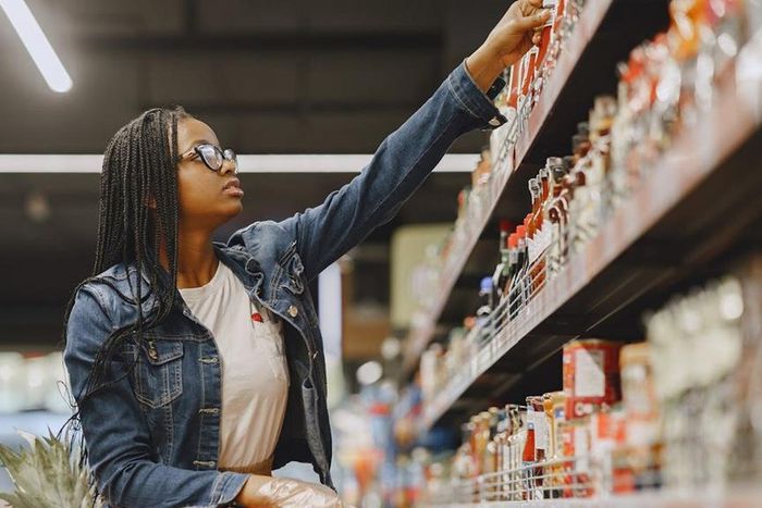 A customer checks labels on products on a supermarket shelf [Image Credit: Gustavo Fring]