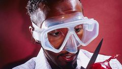 A stock photo of a man wearing a mask to cut an onion