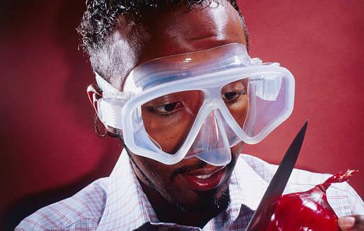 A stock photo of a man wearing a mask to cut an onion