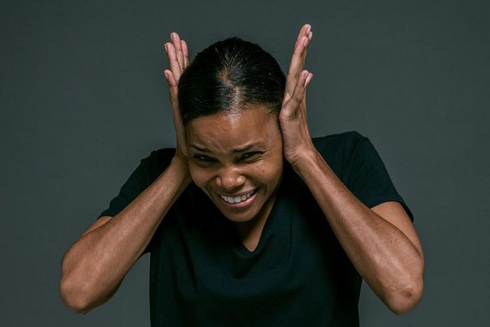 Woman in black v-neck t-shirt covering her ears [Photo: Ketut Subiyanto]