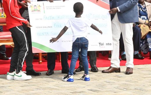 President William Ruto hands Faith Kipyegon a dummy cheque of Sh5 million at State House, Nairobi on June 13, 2023