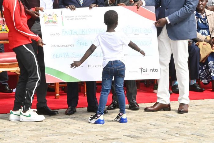 President William Ruto hands Faith Kipyegon a dummy cheque of Sh5 million at State House, Nairobi on June 13, 2023