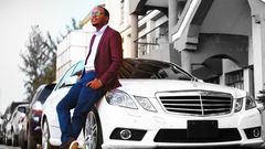 Abel Mutua poses next to his Mercedes Benz E250