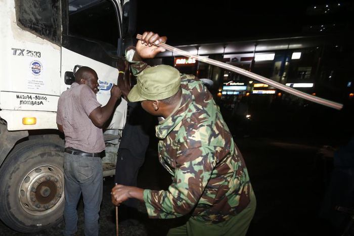 Police canning a driver caught outside during curfew hours