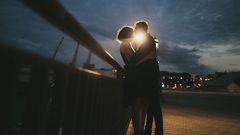 Caucasian couple kissing near railing at night