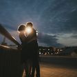 Caucasian couple kissing near railing at night
