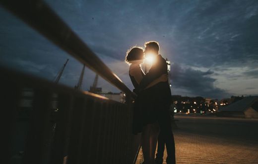Caucasian couple kissing near railing at night