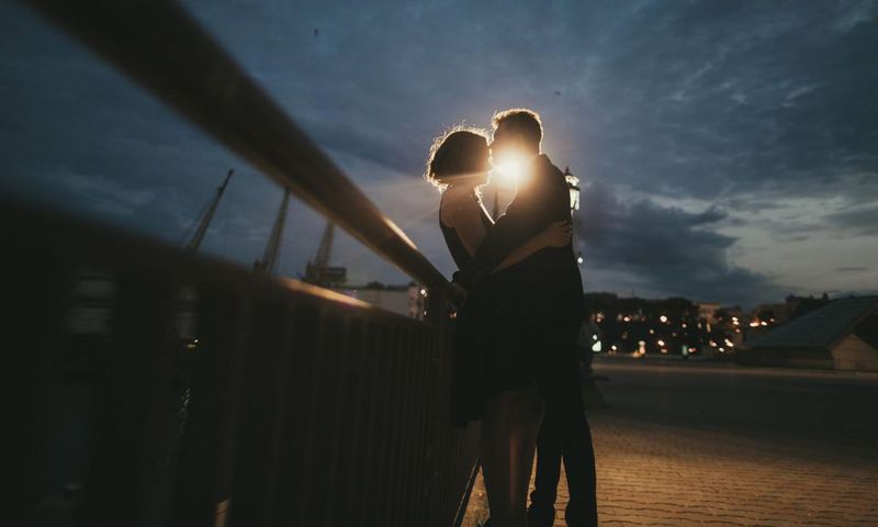 Caucasian couple kissing near railing at night
