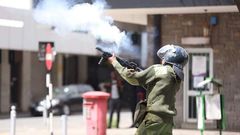 A Police officer fires a teargas to protestors