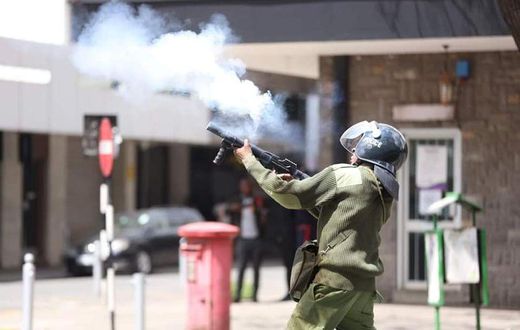 A Police officer fires a teargas to protestors