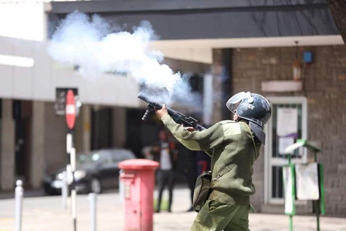 A Police officer fires a teargas to protestors