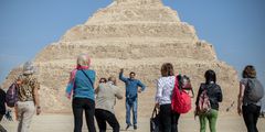 Tourists take souvenir pictures in front of the Pyramid of Djoser in Saqqara outside Cairo.