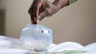 A person putting a coin into a savings piggy bank [Image credit: Joslyn Pickens]