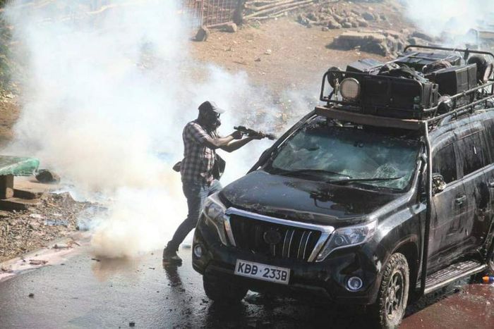 Police officer capture firing teargas at close range into vehicle during protests in Nairobi on March 30, 2023