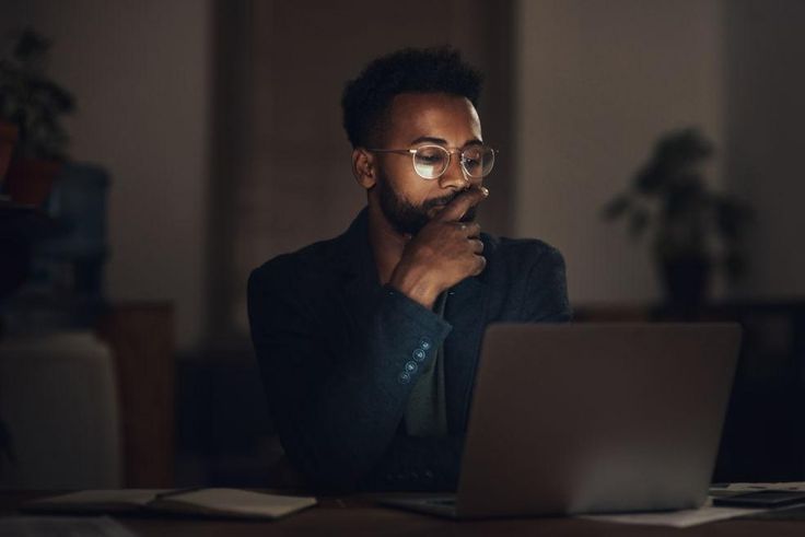 Shot of a young businessman using a laptop during a late night at work