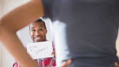 Man showing 'I'm Sorry' sign to angry girlfriend