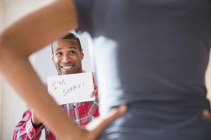 Man showing 'I'm Sorry' sign to angry girlfriend