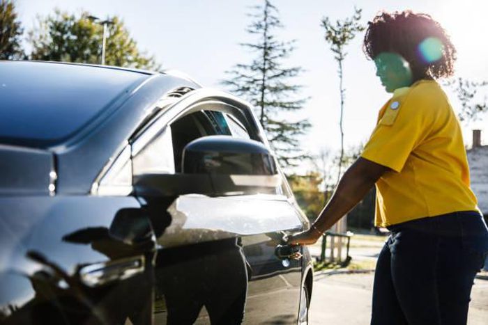 Young woman opening the car door. Credit: Fotostorm
