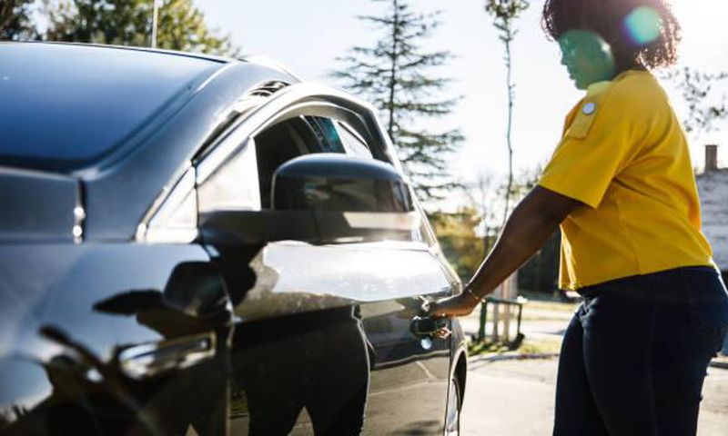 Young woman opening the car door. Credit: Fotostorm