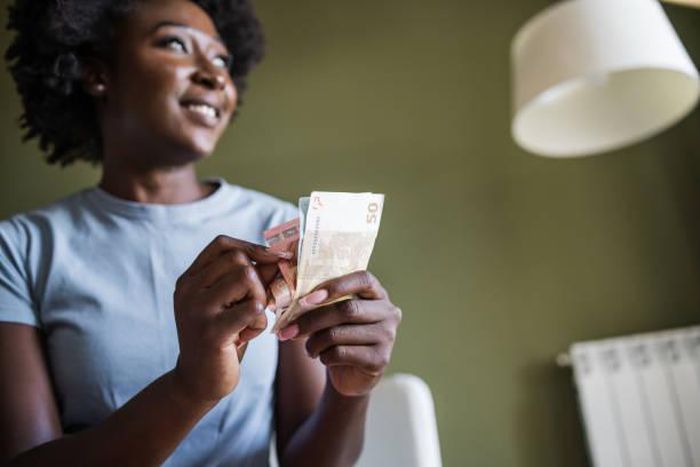 A woman at home counting money. Photo credits: Riska
