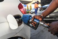 A pump attendant fills a car with fuel (Photo by SIMON MAINA/AFP via Getty Images)