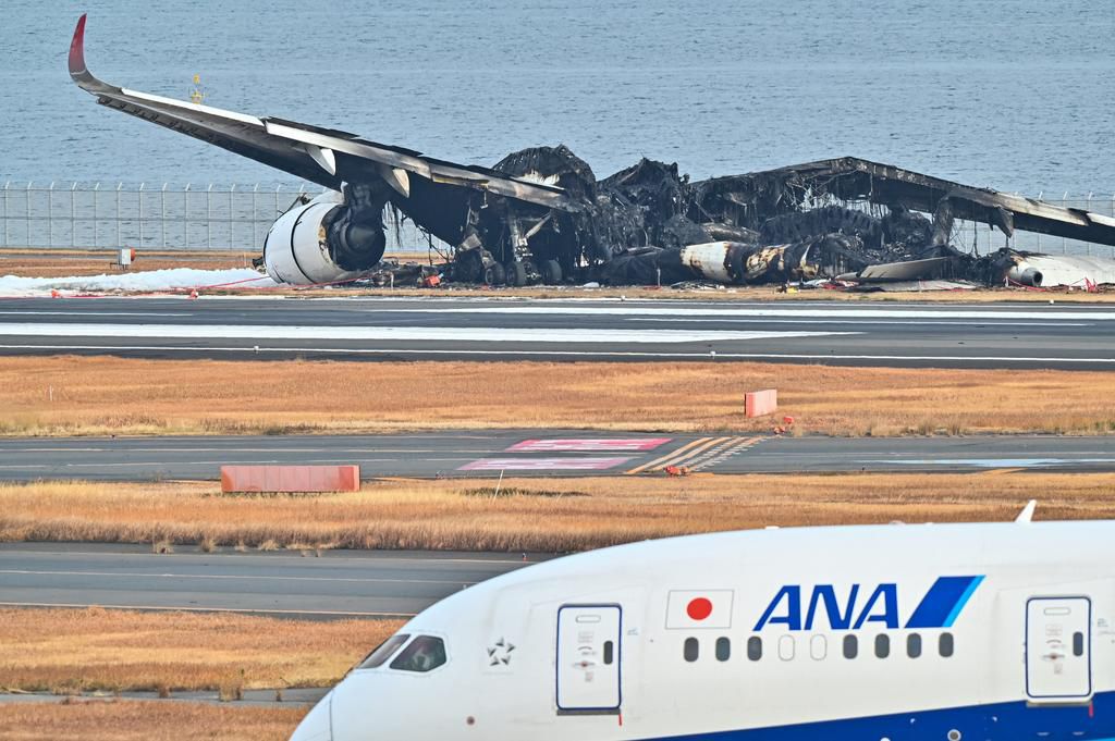An All Nippon Airlines (ANA) plane taxis past the burnt wreckage of a Japan Airlines (JAL) passenger plane at Tokyo International Airport on January 3, 2024.Richard A. Brooks/AFP/Getty Images
