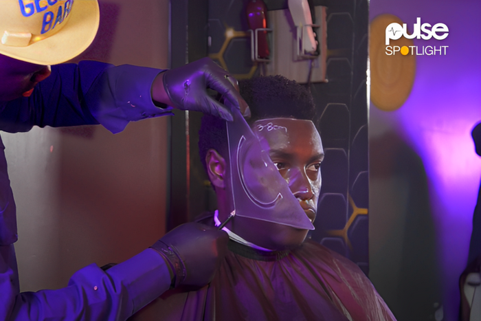 Zachariah Mwaura shaving a client with geometric tools
