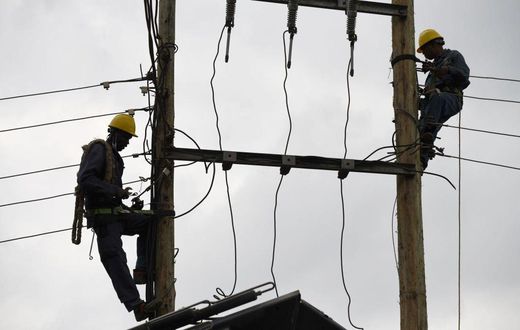 [FILE] Kenya Power and Lighting Company (KPLC) live line experts dismantle power cables to relocate power lines to pave way for the construction of the Nairobi Expressway in Westlands, Nairobi, on September 24, 2020. (Photo by SIMON MAINA/AFP via Getty...