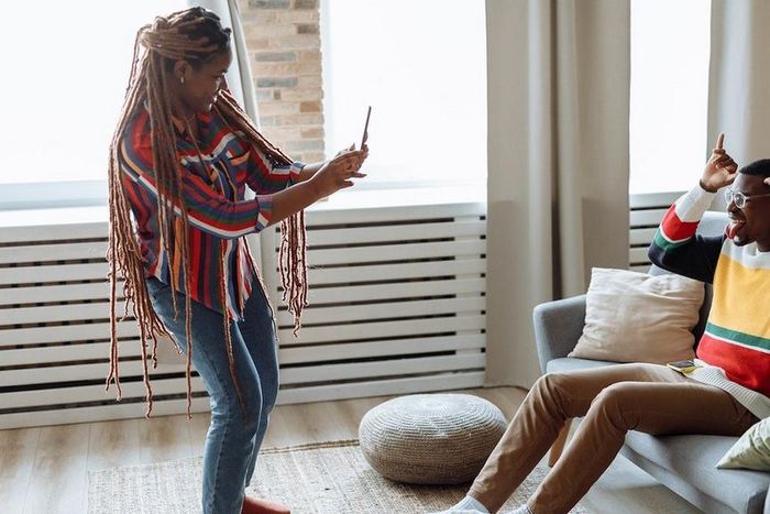 A woman taking photo of a man sitting on a sofa [Photo: Thirdman]