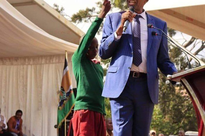 Young learner holding an umbrella for CS Machogu during a public function in Murang'a
