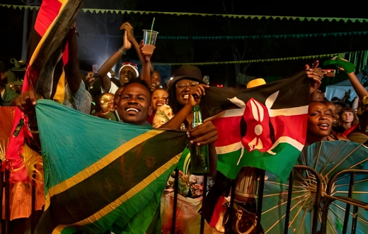 Festival-goers wave flags of Tanzania and Kenya. (Photo by BADRU KATUMBA / AFP)