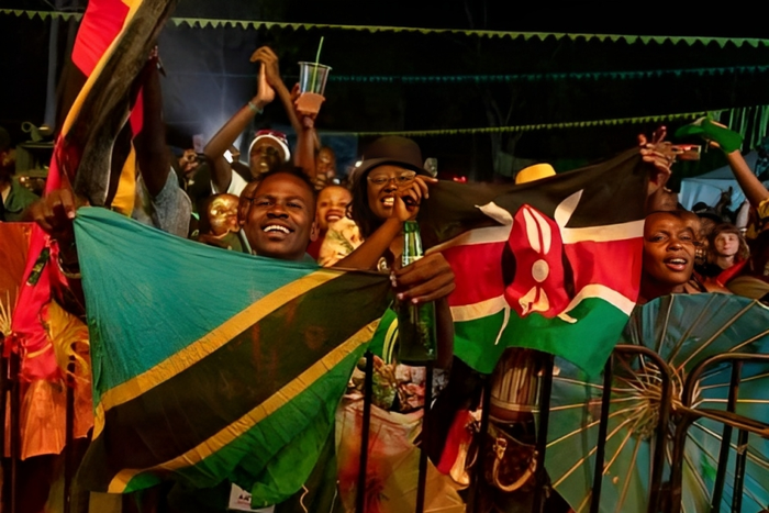 Festival-goers wave flags of Tanzania and Kenya. (Photo by BADRU KATUMBA / AFP)