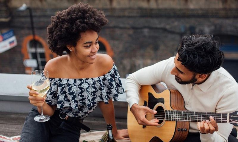 Man holding an acoustic guitar beside a woman [Photo: Viktoria Slowikowska]