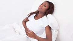 ___7975596___2018___2___13___9___a-woman-is-lying-in-bed-holding-her-stomach