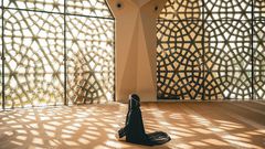 Woman praying in a mosque with openwork windows {image Credit: Hatice Baran]