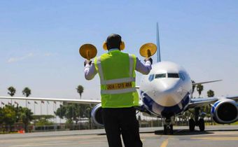 An aircraft marshal guides a plane at JKIA