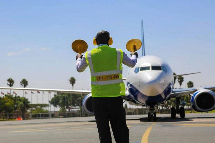 An aircraft marshal guides a plane at JKIA