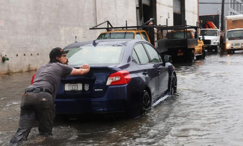 A man pushes a car through the flooded streets of Red Hook in Brooklyn on September 29, 2023.Spencer Platt/Getty Images
