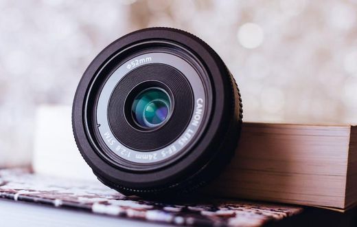 Canon zoom lens leaning on book [Image: Freestocks.org]