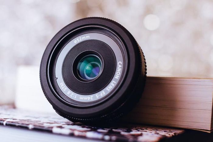 Canon zoom lens leaning on book [Image: Freestocks.org]