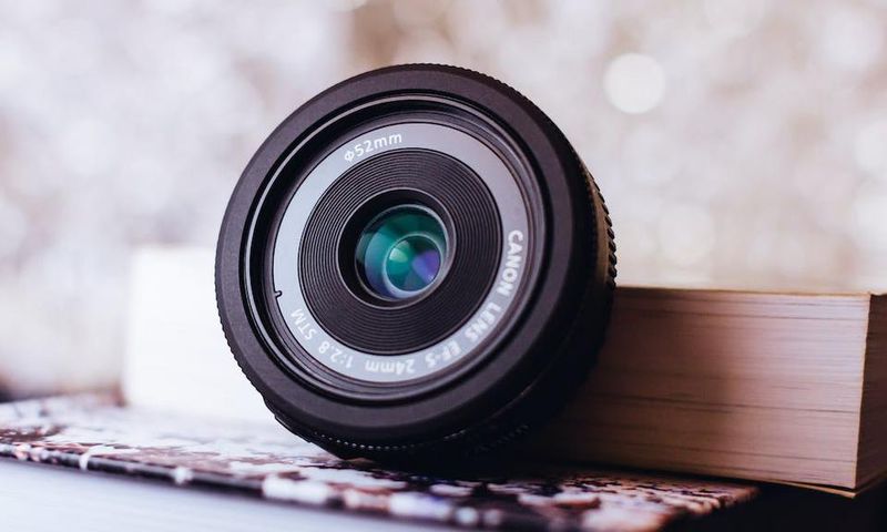 Canon zoom lens leaning on book [Image: Freestocks.org]