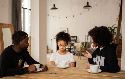 Black parents lecturing upset daughter at table [Credit: Monstera Production]