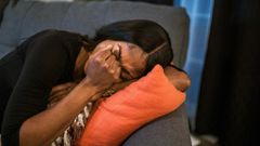 Sad woman in black shirt lying on pillow on a sofa [Photo: RDNE Stock Project]