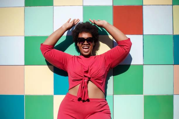 Stylish woman looking excited against multicolored tiled wall - stock photo ( Luis Alvarez)