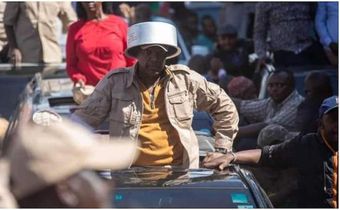 Azimio la Umoja leader Jeremiah Kioni puts a sufuria on his head during a past