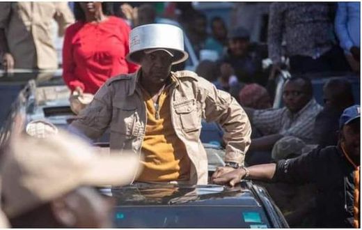 Azimio la Umoja leader Jeremiah Kioni puts a sufuria on his head during a past