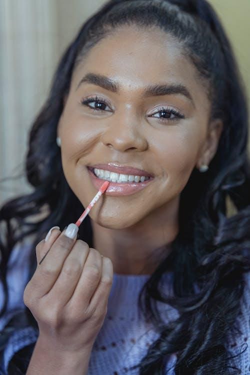 A lady applying lip gloss during beauty routine