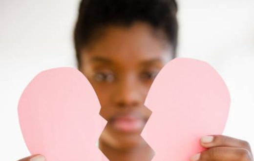 Woman holding a broken paper heart